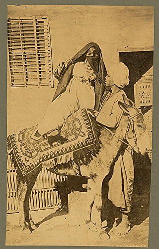 צילום היסטוריים: אישה בסיוע גבר כשהיא מתנשאת או מפרקת חמור באלכסנדריה, מצרים